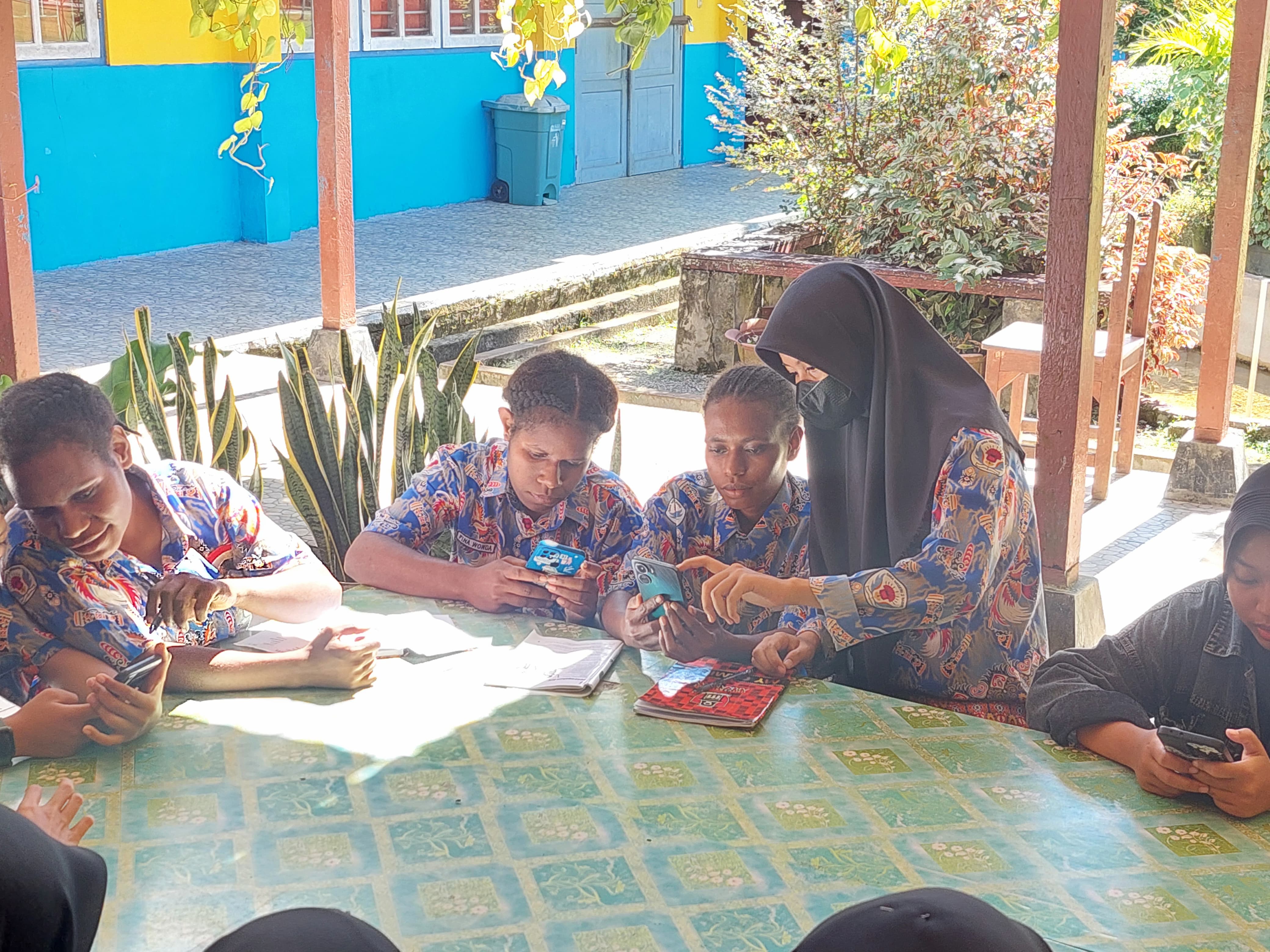A woman wearing a hijab helps a students at a table with school work.