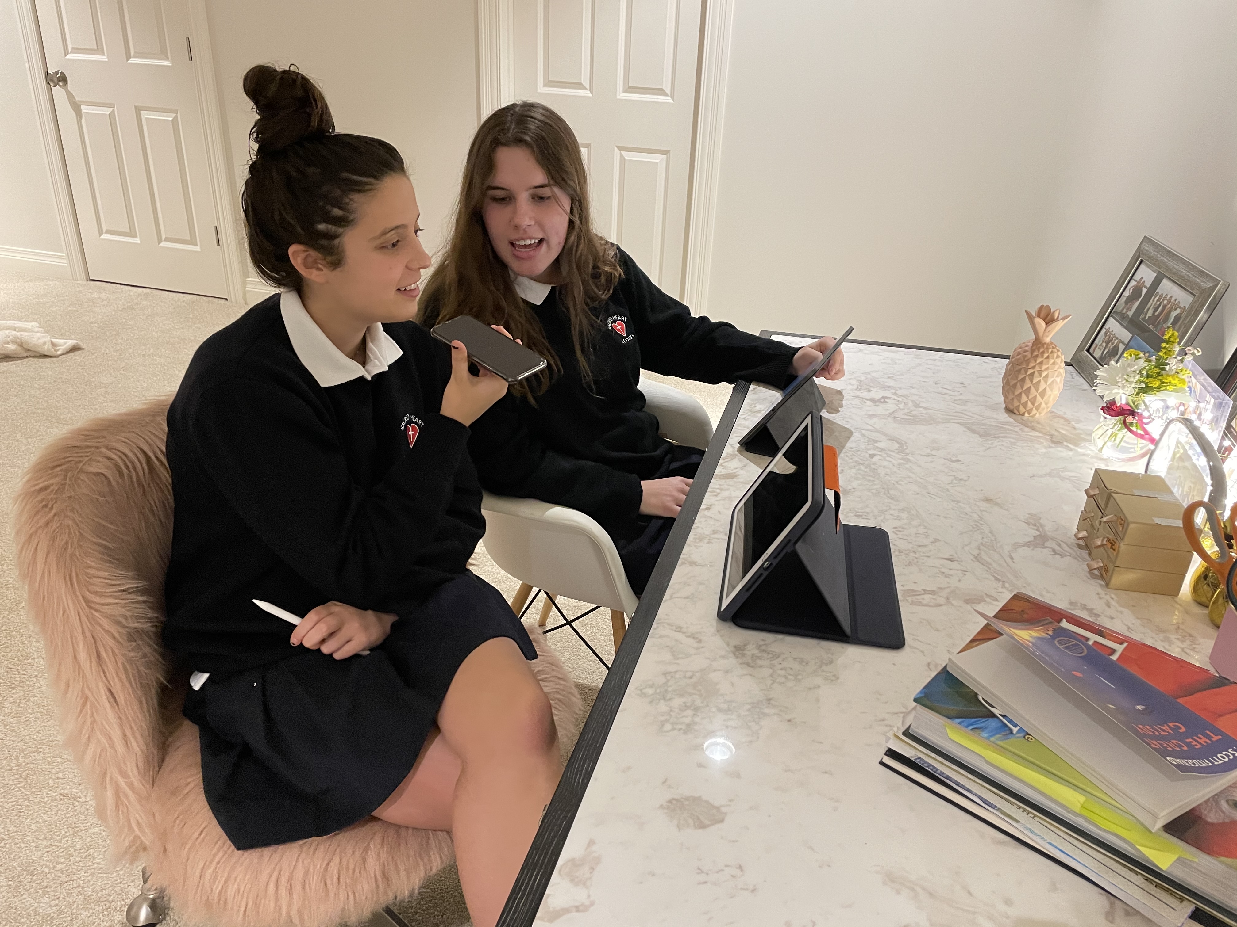 Jacqueline and Amelie sitting at a white desk working on their project.