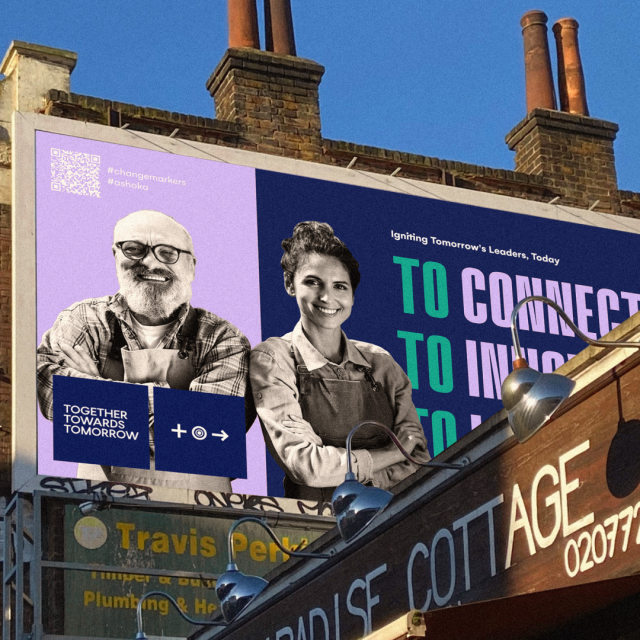 A photoshopped image of an advertisement for the Together Towards Tomorrow Changemaker Challenge superimposed onto a billboard featuring both the brand colors, a photo of group of people in black and white, and text..