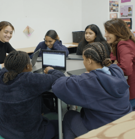 Teacher and students around a table with their laptops